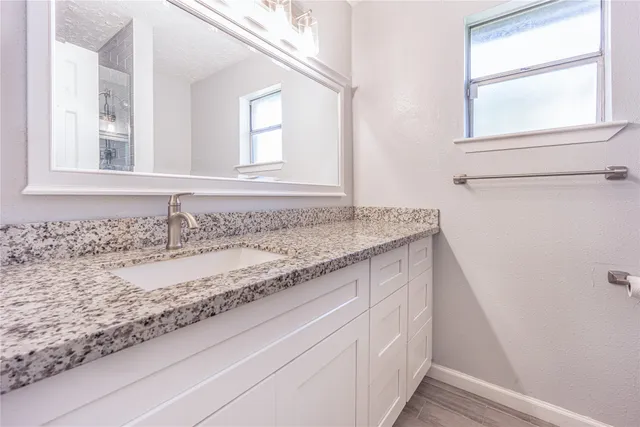 a bathroom with a granite countertop sink and a window