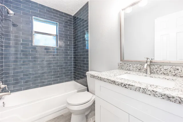 a bathroom with a granite countertop bathtub sink vanity mirror and toilet