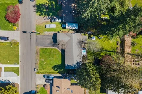 an aerial view of a house with swimming pool and large trees