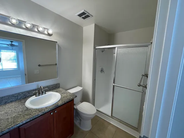 a bathroom with a granite countertop sink toilet a shower and a mirror