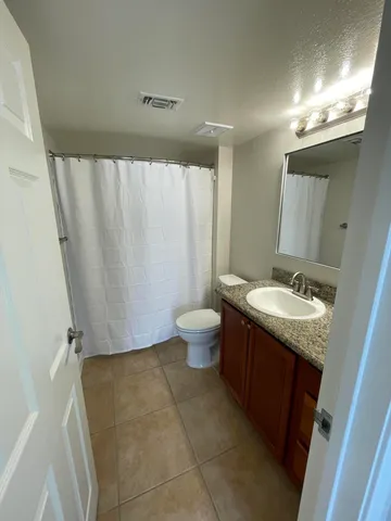 a bathroom with a granite countertop sink toilet and a mirror