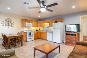 a kitchen with stainless steel appliances kitchen island granite countertop a refrigerator a stove a sink a dining table and chairs with wooden floor