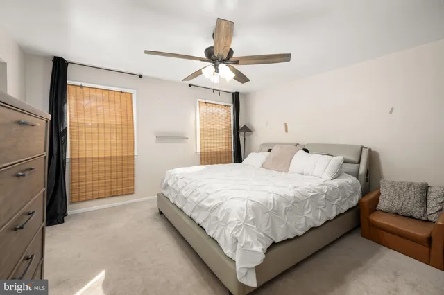 a bedroom with a large bed and a chandelier fan