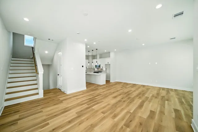 a view of a kitchen with kitchen island a sink wooden floor and a refrigerator
