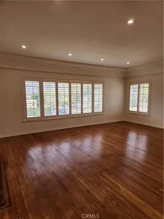 a view of an empty room with wooden floor and window