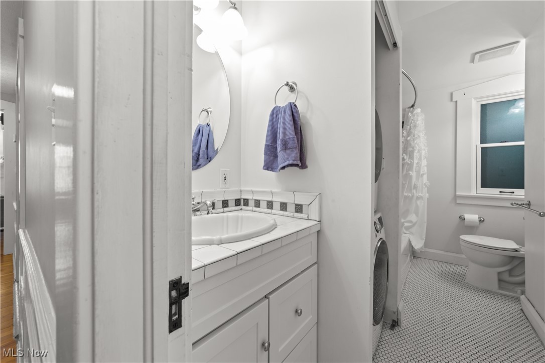 2472 Overlook Road, Unit 3 Cleveland, OH 44106 - Photo 8 of 11 Full bathroom featuring tile patterned flooring, visible vents, stacked washer / dryer, toilet, and vanity