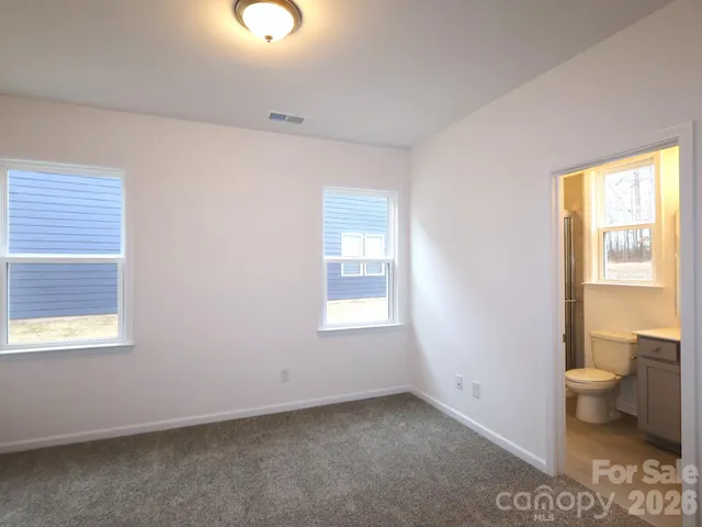 a view of an empty room with a window and bathroom