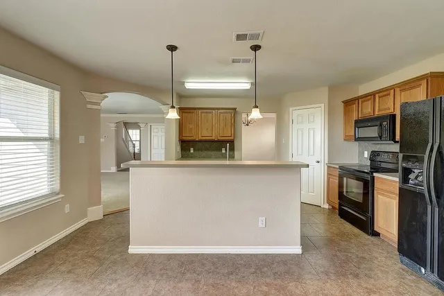 a kitchen with kitchen island a counter top space appliances and a window