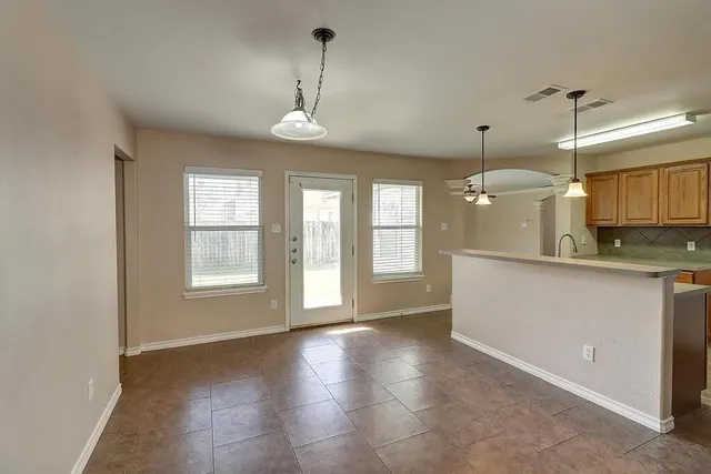 a view of an empty room with window and chandelier