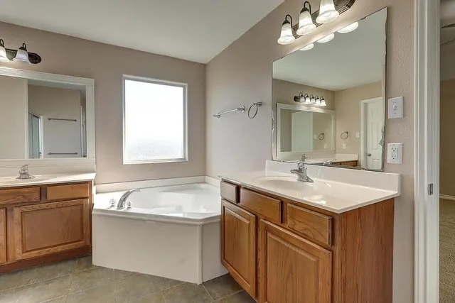a bathroom with a sink double vanity granite tub and a mirror