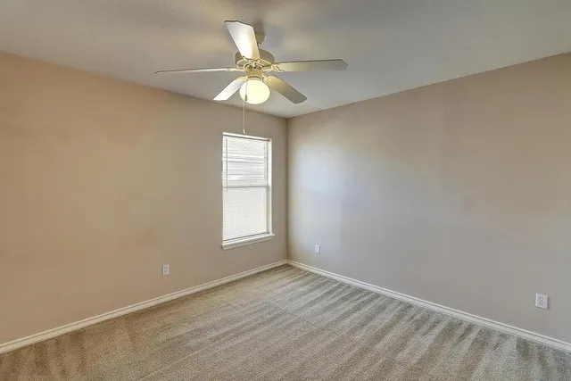 an empty room with a window and a fan