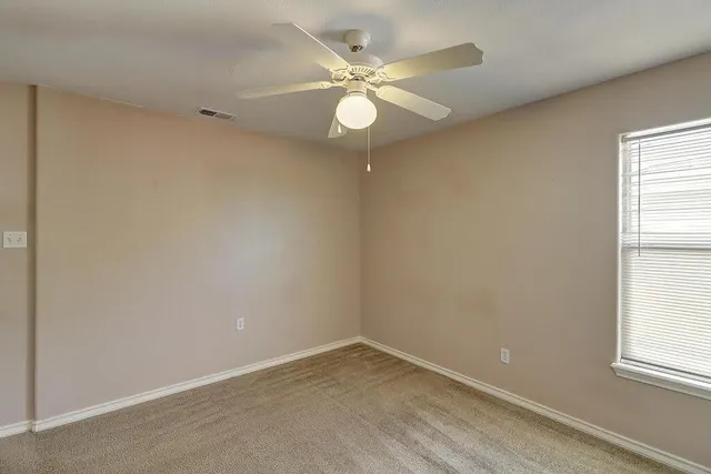 an empty room with windows and fan