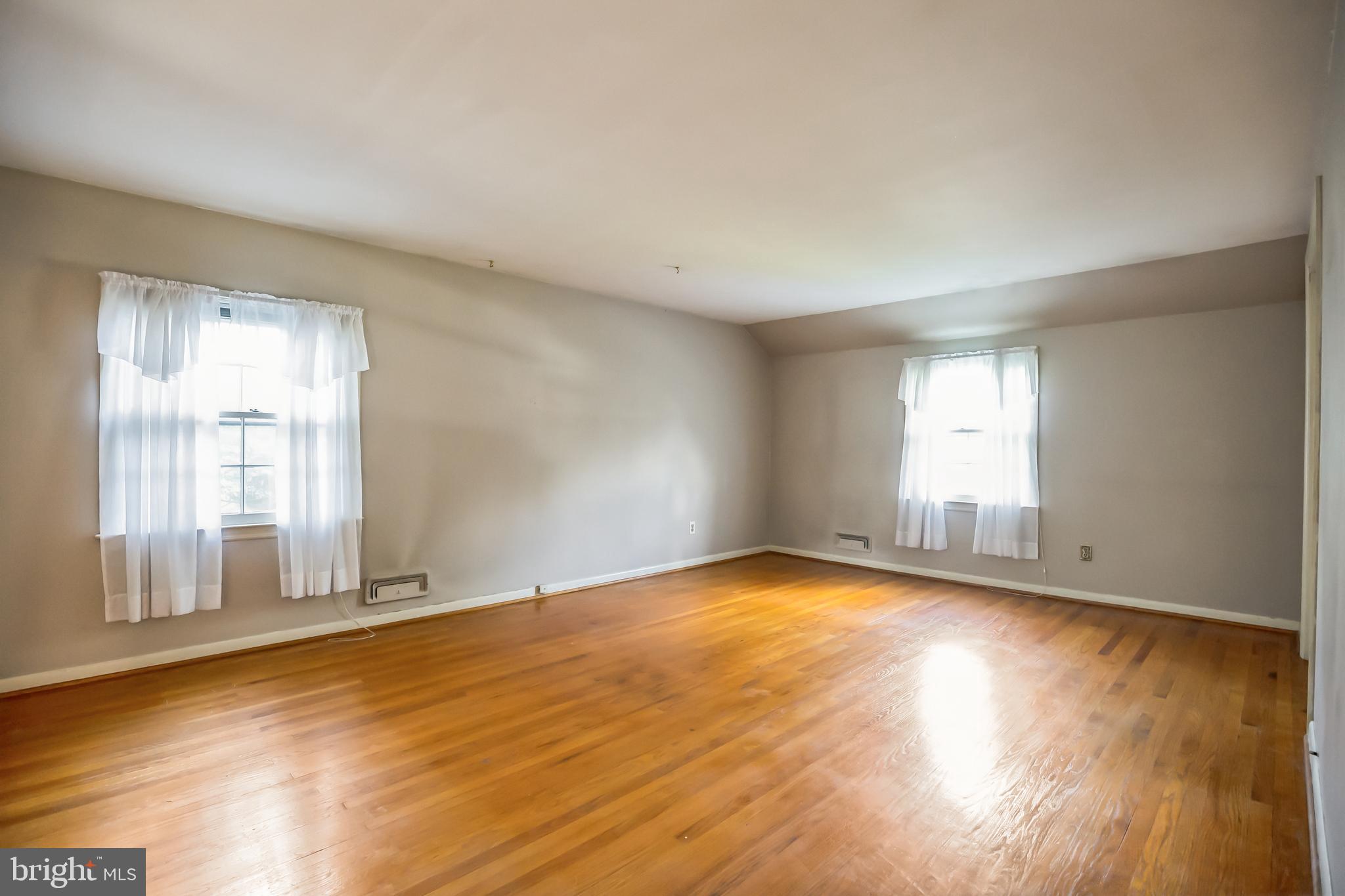 121 Rockingham Road Cherry Hill, NJ 08034 - Photo 21 of 33 an empty room with wooden floor and windows with curtains view