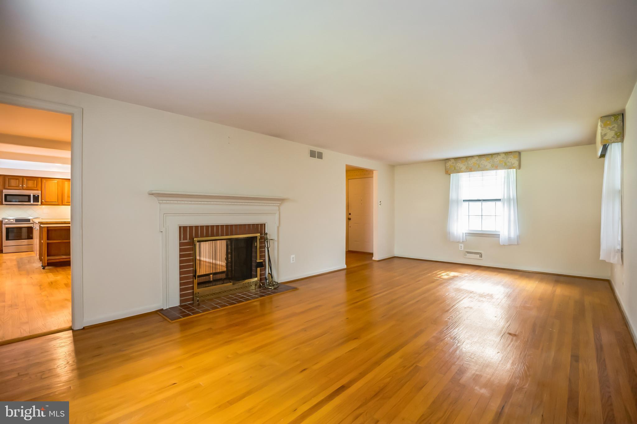 121 Rockingham Road Cherry Hill, NJ 08034 - Photo 6 of 33 an empty room with wooden floor fireplace and windows