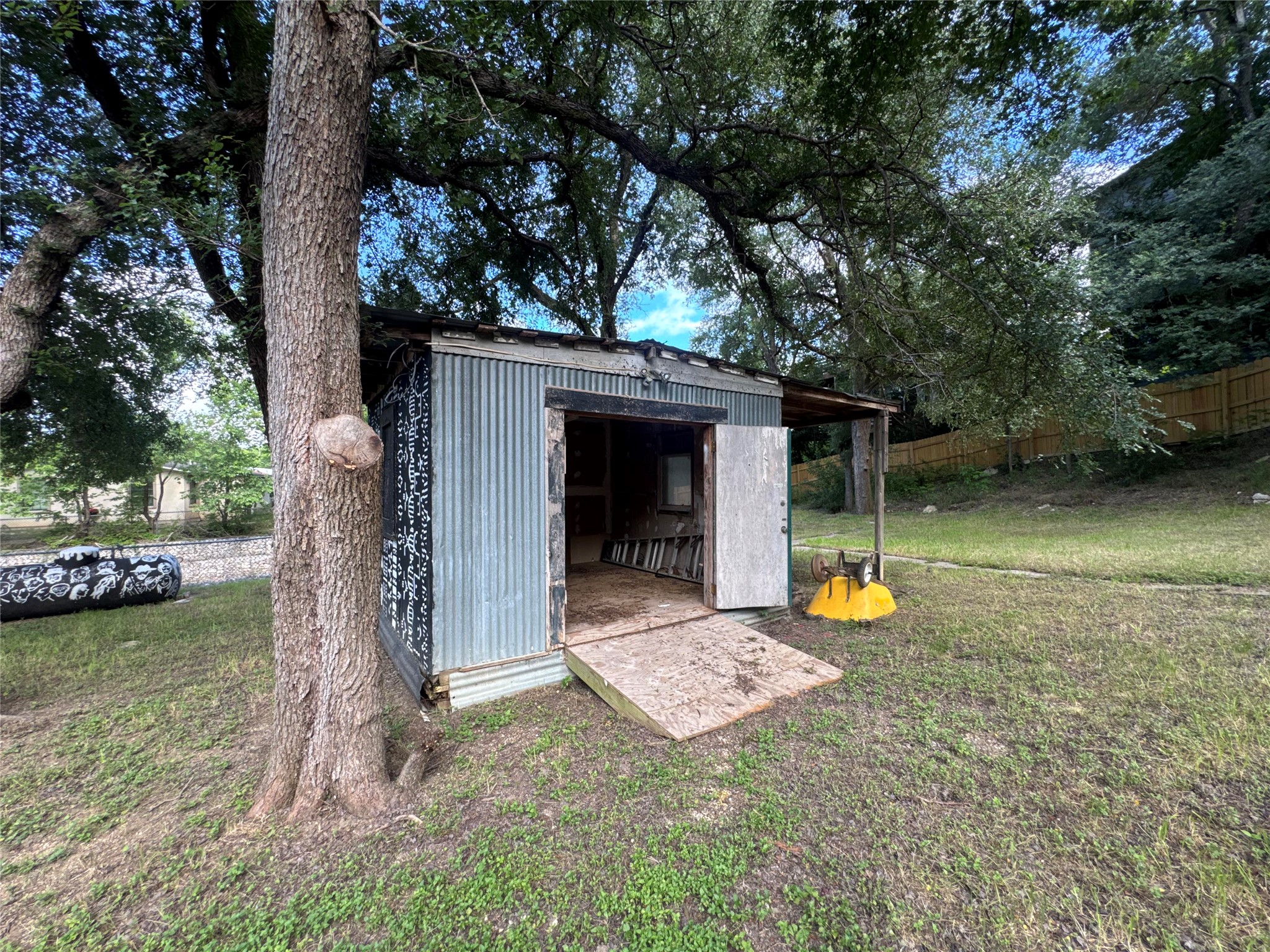 5007 Heflin Lane Austin, TX 78721 - Photo 19 of 25 A quaint storage shed nestled amidst verdant trees offers practical outdoor utility.