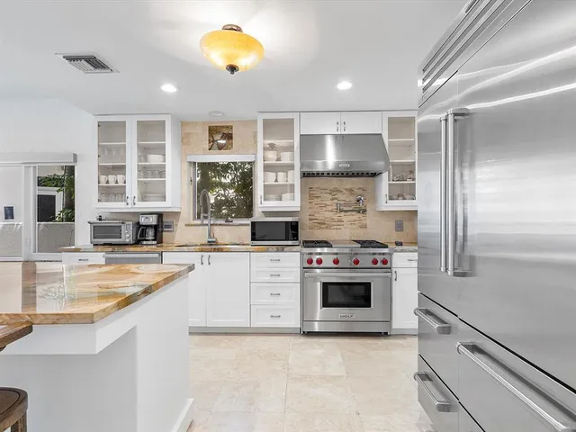 a kitchen with stainless steel appliances kitchen island granite countertop a table chairs sink and cabinets