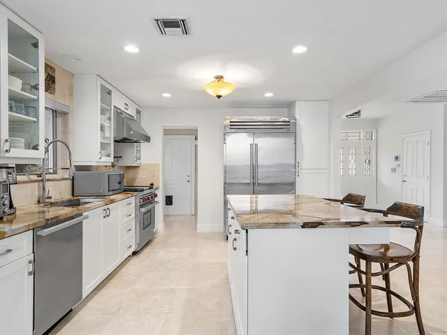 a view of a kitchen with kitchen island white cabinets and stainless steel appliances