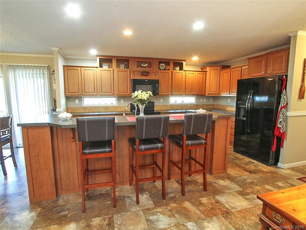 4027 Pink Plyler Road Lancaster, SC 29720 - Photo 21 of 34 a kitchen with stainless steel appliances kitchen island granite countertop sink refrigerator dining table and chairs