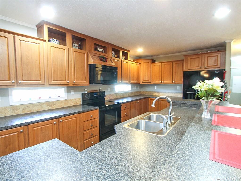 4027 Pink Plyler Road Lancaster, SC 29720 - Photo 23 of 34 a kitchen with stainless steel appliances granite countertop a sink a stove and a granite counter tops with white cabinets
