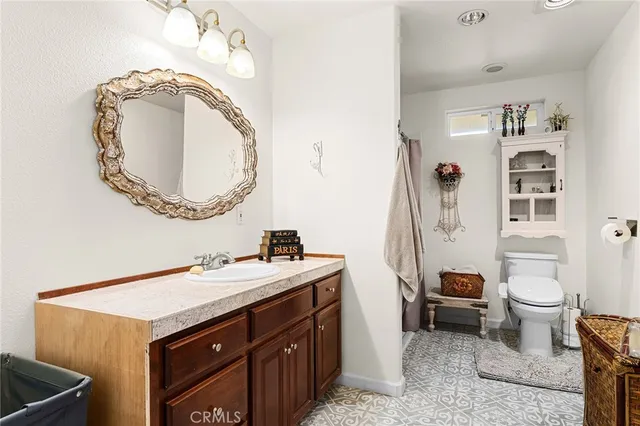 a bathroom with a granite countertop double vanity sink mirror and toilet