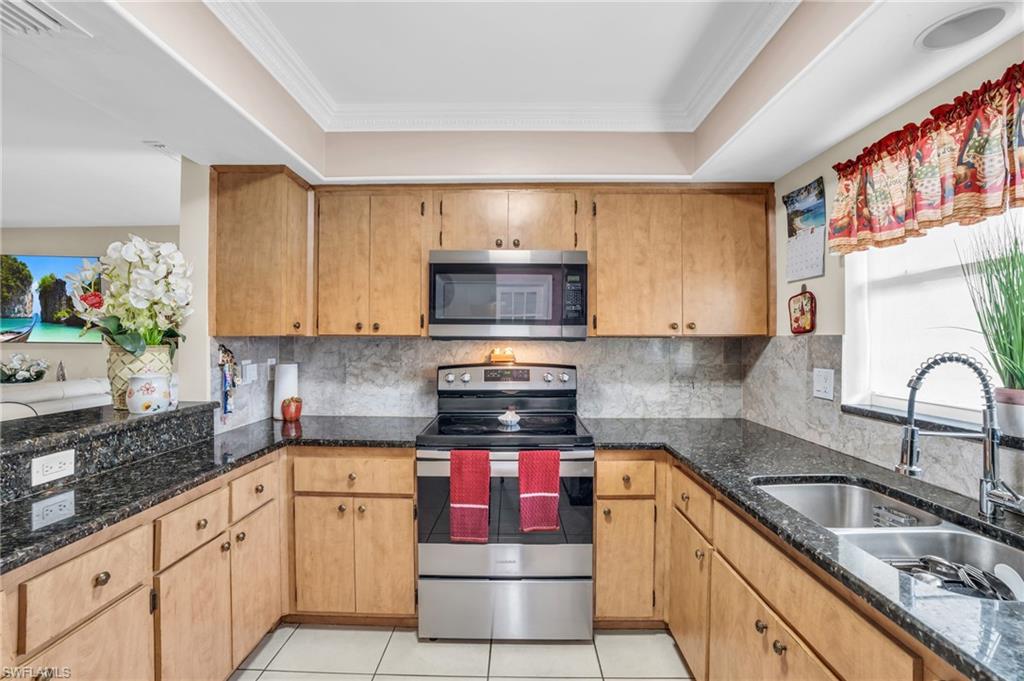 4333 20th Place Southwest Naples, FL 34116 - Photo 7 of 31 a kitchen with stainless steel appliances granite countertop a stove a sink and a microwave