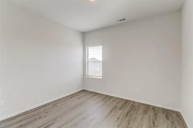 a view of an empty room with wooden floor and window