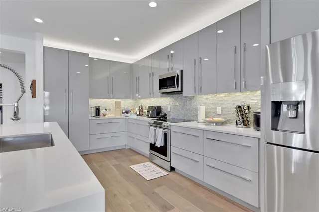 a kitchen with stainless steel appliances granite countertop a refrigerator sink and white cabinets