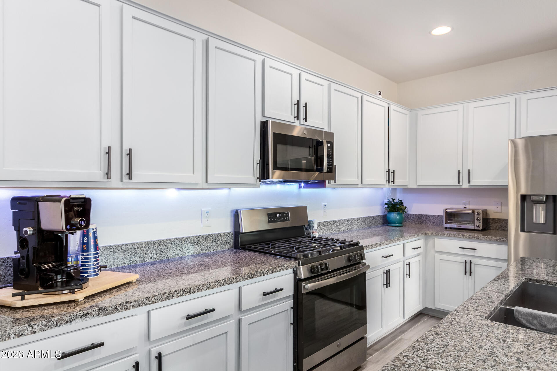 21057 West Almeria Road Buckeye, AZ 85396 - Photo 10 of 49 a kitchen with granite countertop a sink stainless steel appliances and white cabinets