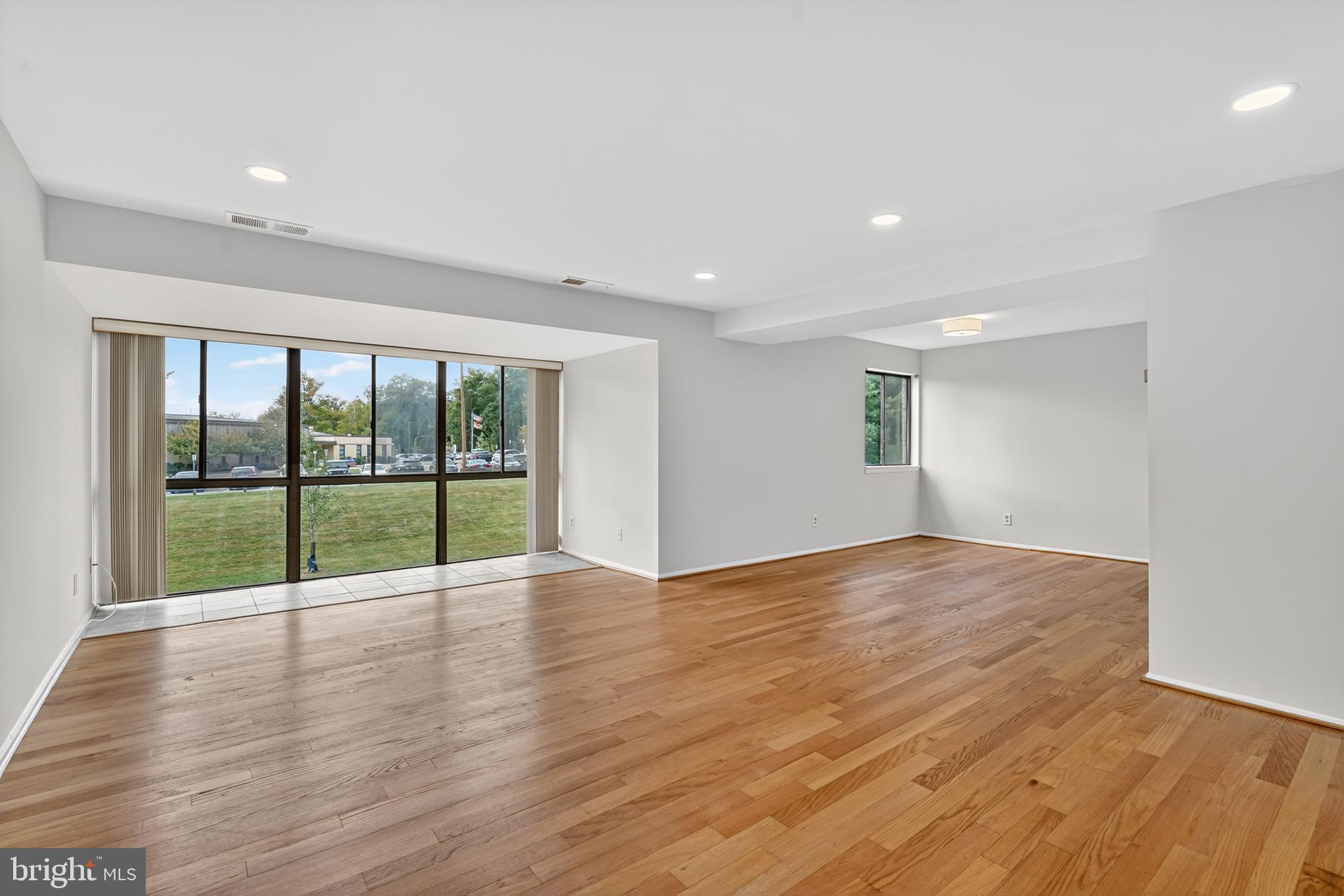 18910 Smoothstone Way, Unit 4 Montgomery Village, MD 20886 - Photo 3 of 30 a view of an empty room with wooden floor and a floor to ceiling window