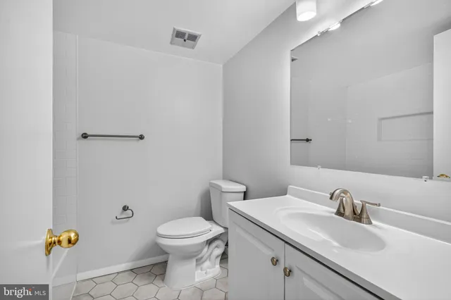 a bathroom with a granite countertop toilet a sink and a mirror
