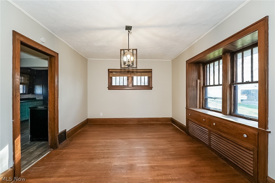 911 Dan Street Akron, OH 44310 - Photo 6 of 20 Empty room with ornamental molding, a notable chandelier, and dark wood-type flooring