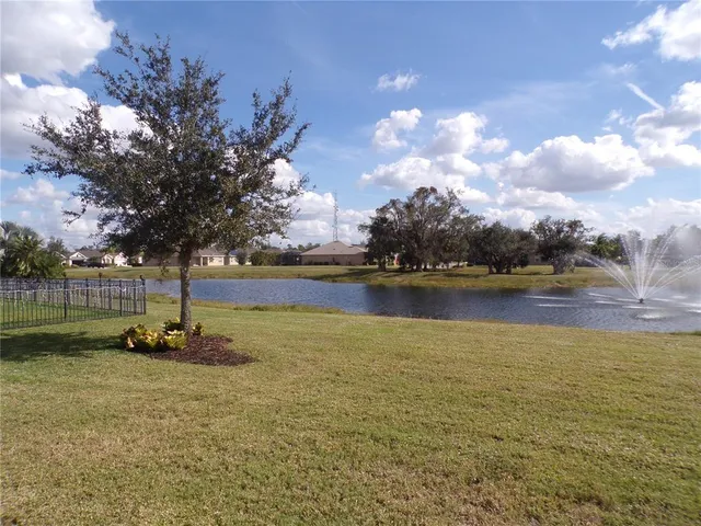 a backyard of a house with lots of green space and lake view in back