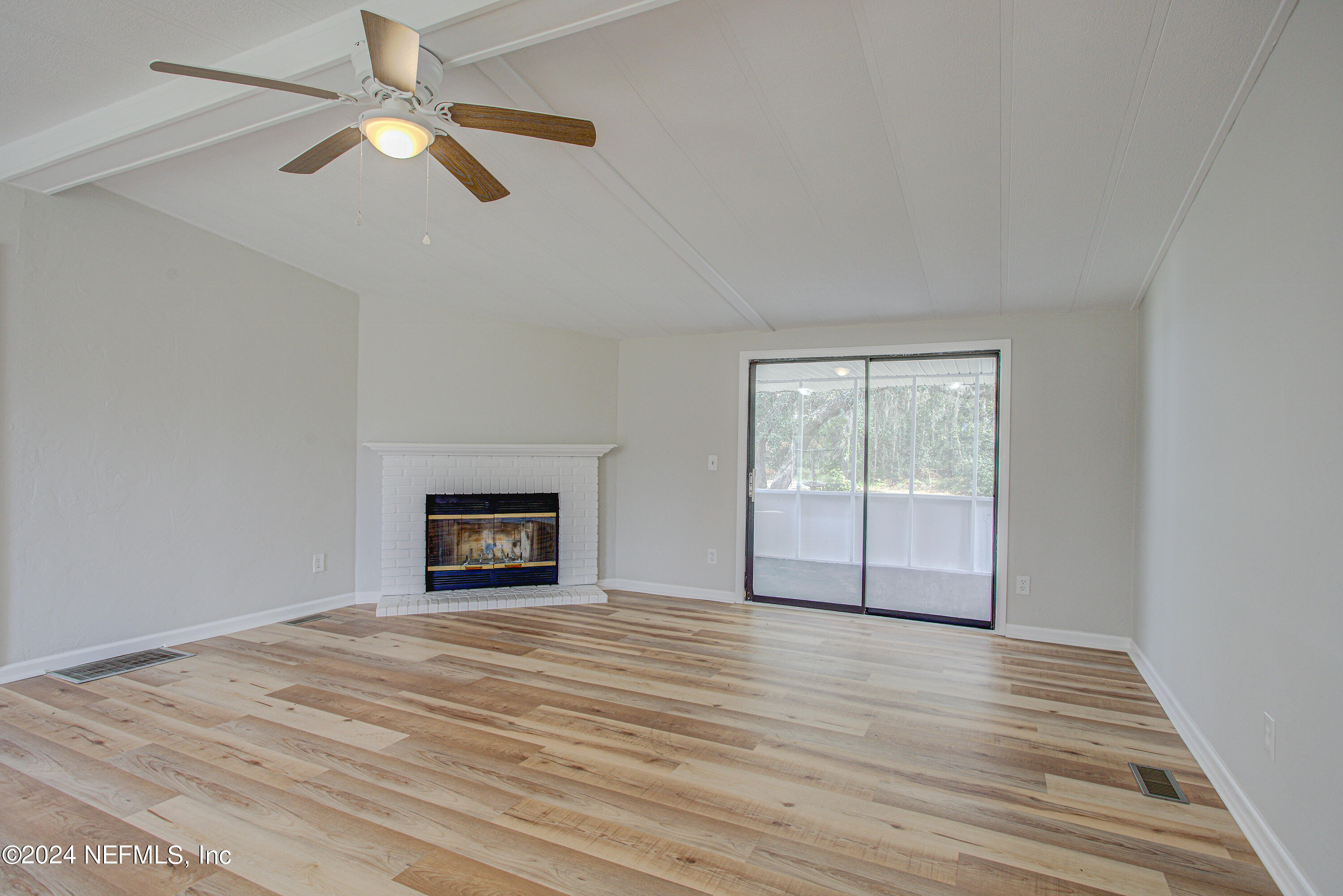 7677 Oak Forest Road Keystone Heights, FL 32656 - Photo 11 of 54 an empty room with wooden floor chandelier fan and windows