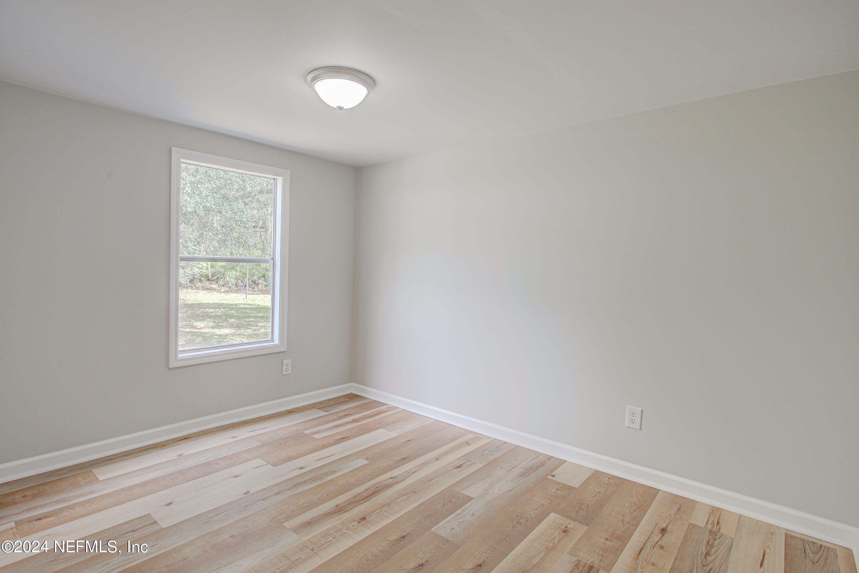 7677 Oak Forest Road Keystone Heights, FL 32656 - Photo 26 of 54 a view of an empty room with wooden floor and a window