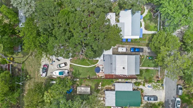 an aerial view of a house with outdoor space and trees all around