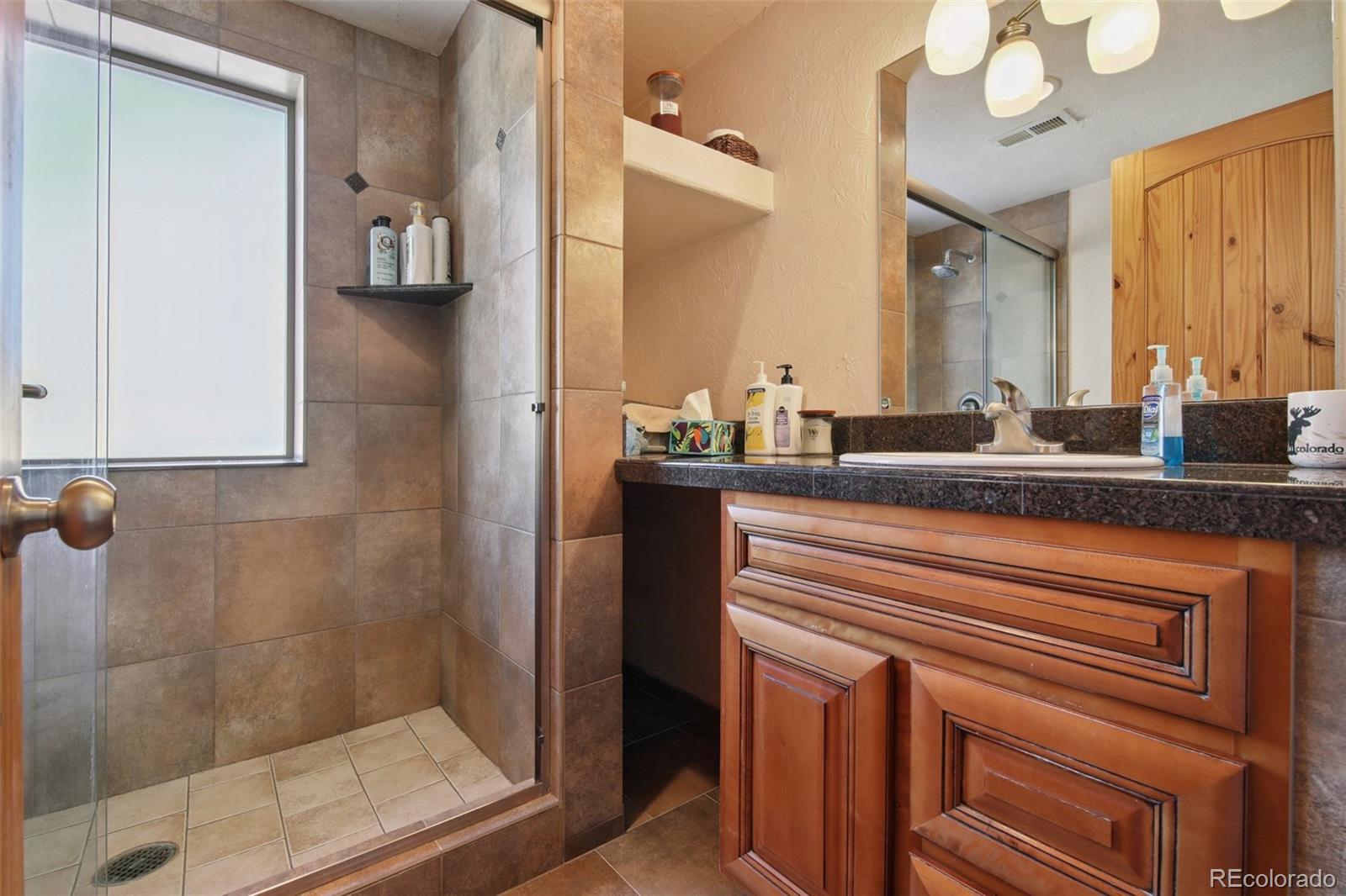 499 Clark Road Bailey, CO 80421 - Photo 14 of 27 a en suite bathroom with a sink a mirror and shower