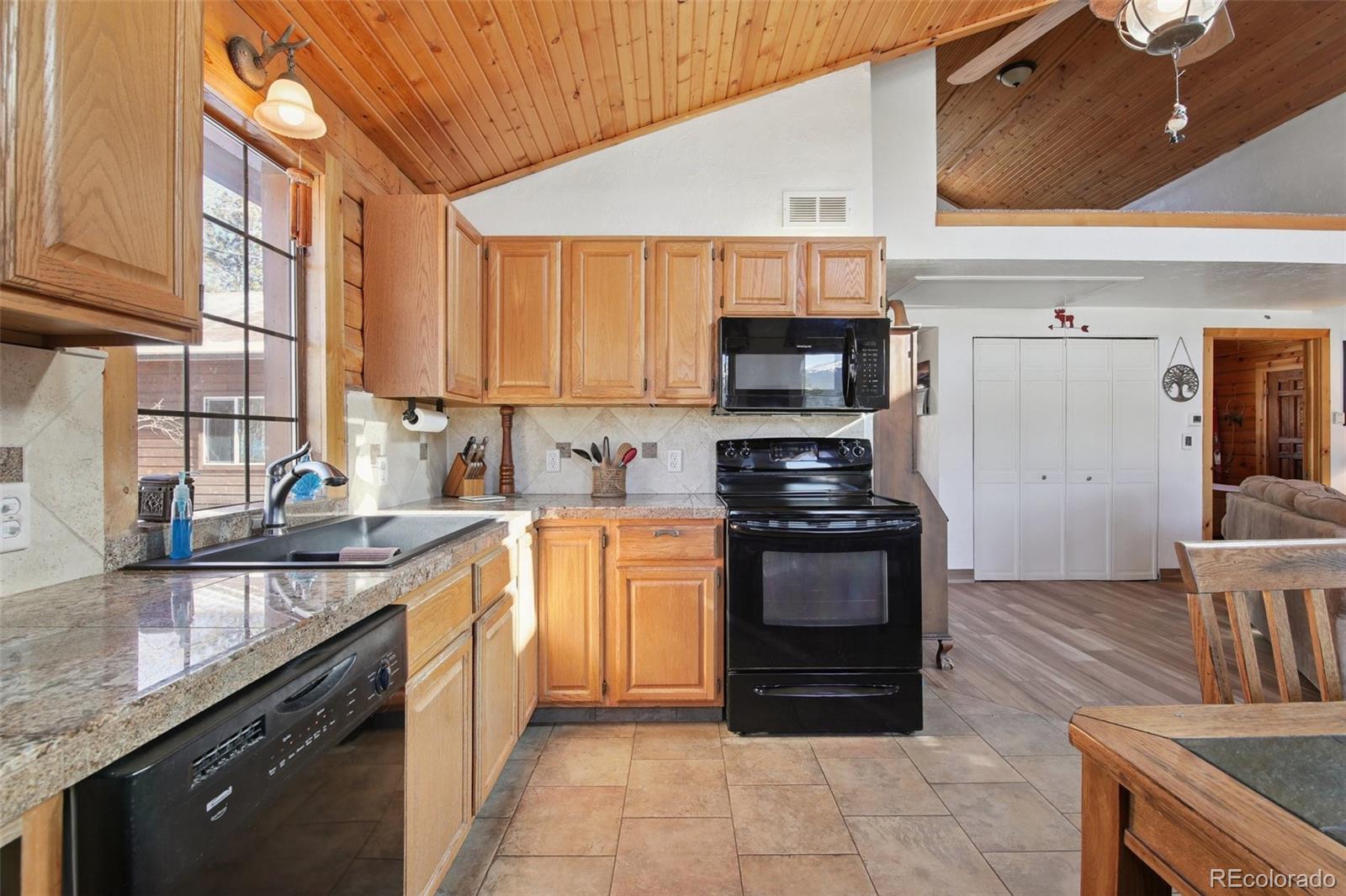 499 Clark Road Bailey, CO 80421 - Photo 9 of 27 a kitchen with stainless steel appliances granite countertop a stove a sink and a microwave
