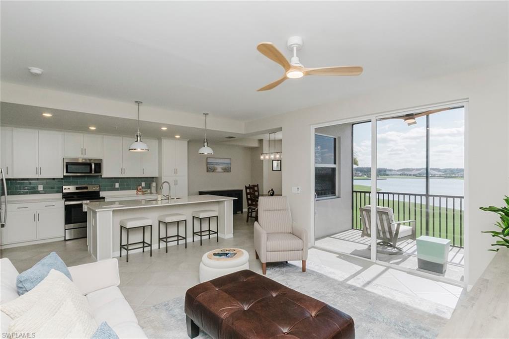 a living room with furniture a floor to ceiling window and wooden floor