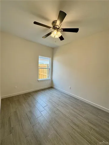 an empty room with wooden floor ceiling fan and windows