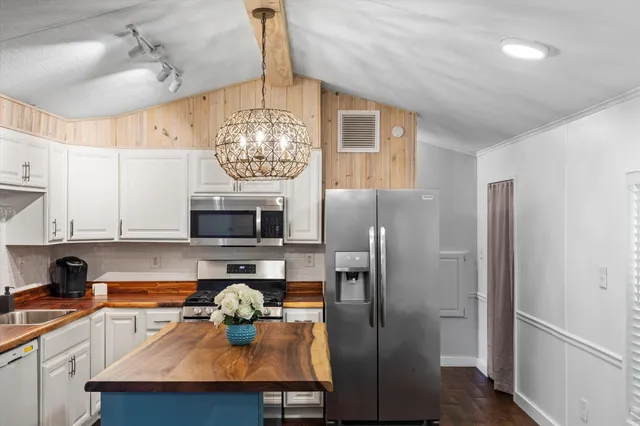 a kitchen with stainless steel appliances a dining table chairs and chandelier