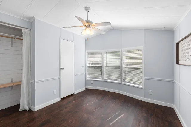 an empty room with wooden floor fan and windows