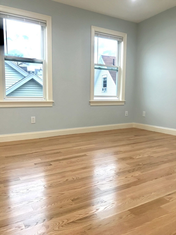 16 Grove Street, Unit 3 Malden, MA 02148 - Photo 4 of 6 an empty room with wooden floor and windows