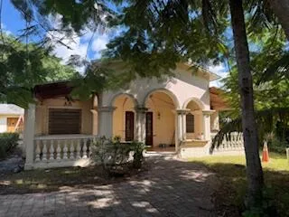 a view of a house with brick walls plants and large tree