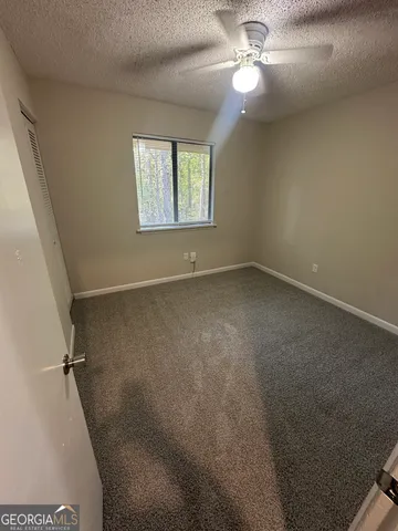 an empty room with windows and fan