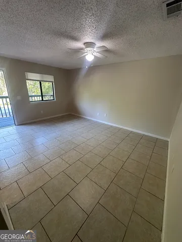 an empty room with windows and ceiling fan