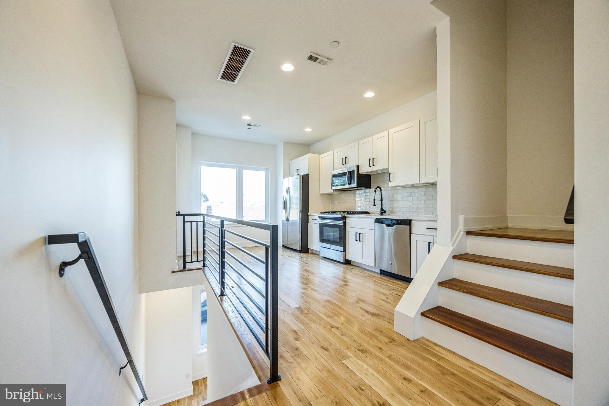 614 Master Street, Unit 2 Philadelphia, PA 19122 - Photo 5 of 29 a open kitchen with white cabinets and stainless steel appliances