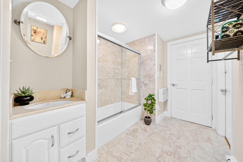 352 Tappan Street, Unit 1 Brookline, MA 02445 - Photo 22 of 42 a bathroom with a granite countertop sink a mirror a vanity and a bathtub