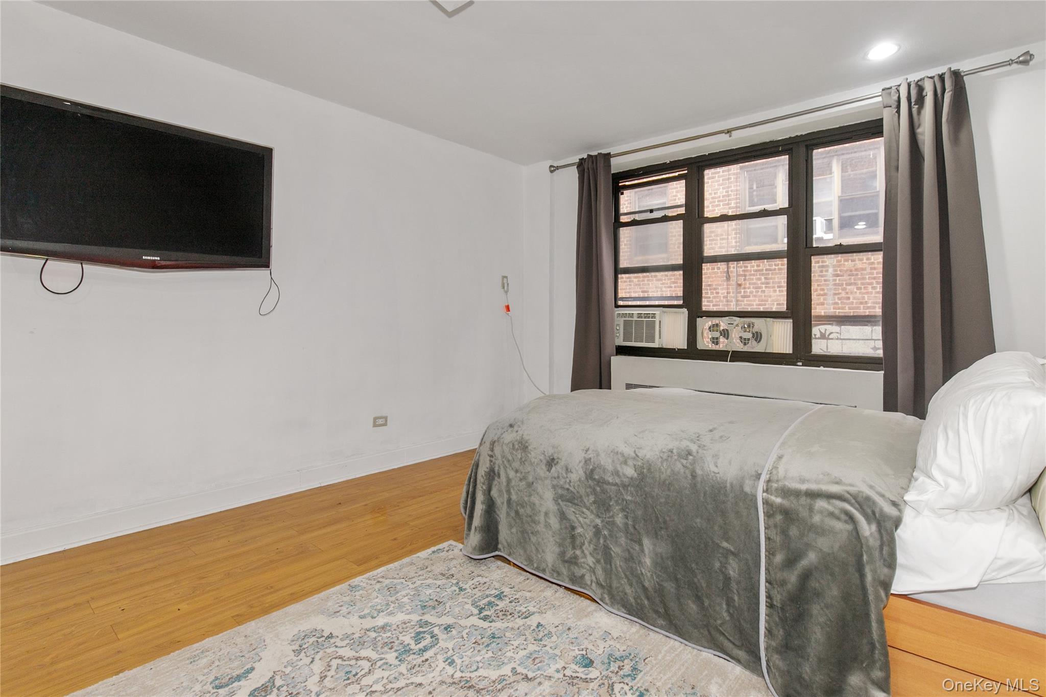 15 Canterbury Road, Unit C10 Great Neck, NY 11021 - Photo 5 of 22 a bedroom with a bed tv and a window