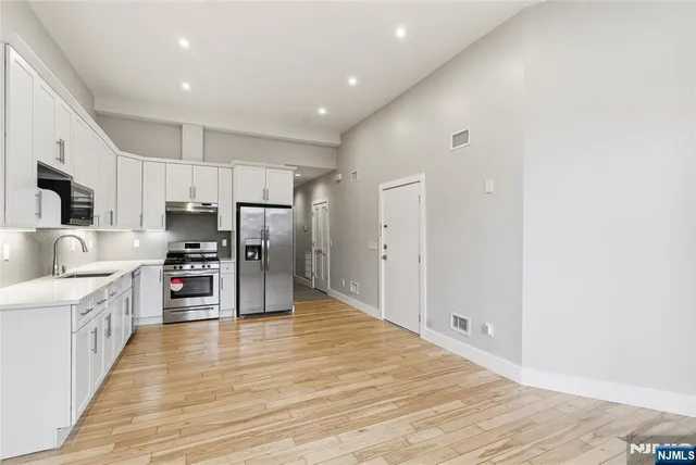 a kitchen with stainless steel appliances a refrigerator and a wooden floor