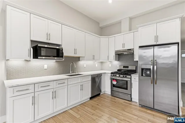 a kitchen with cabinets stainless steel appliances and wooden floor